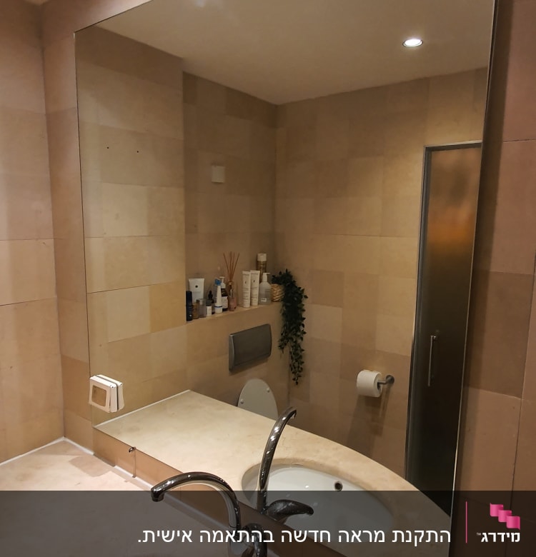 מראה גדולה מעל כיור בחדר אמבטיה